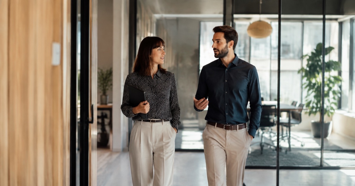 A candidate and recruiter walking through a bright office corridor.